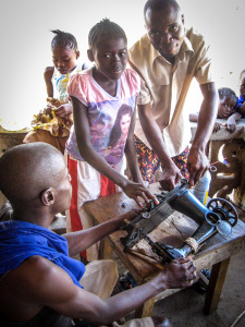 Hawa Kanu, who has been living with us  since her spinal surgery in 2004, and Ansu Kamara with us since 2010, clean an old treadle-sewing machine donated to ASI in 2012.   